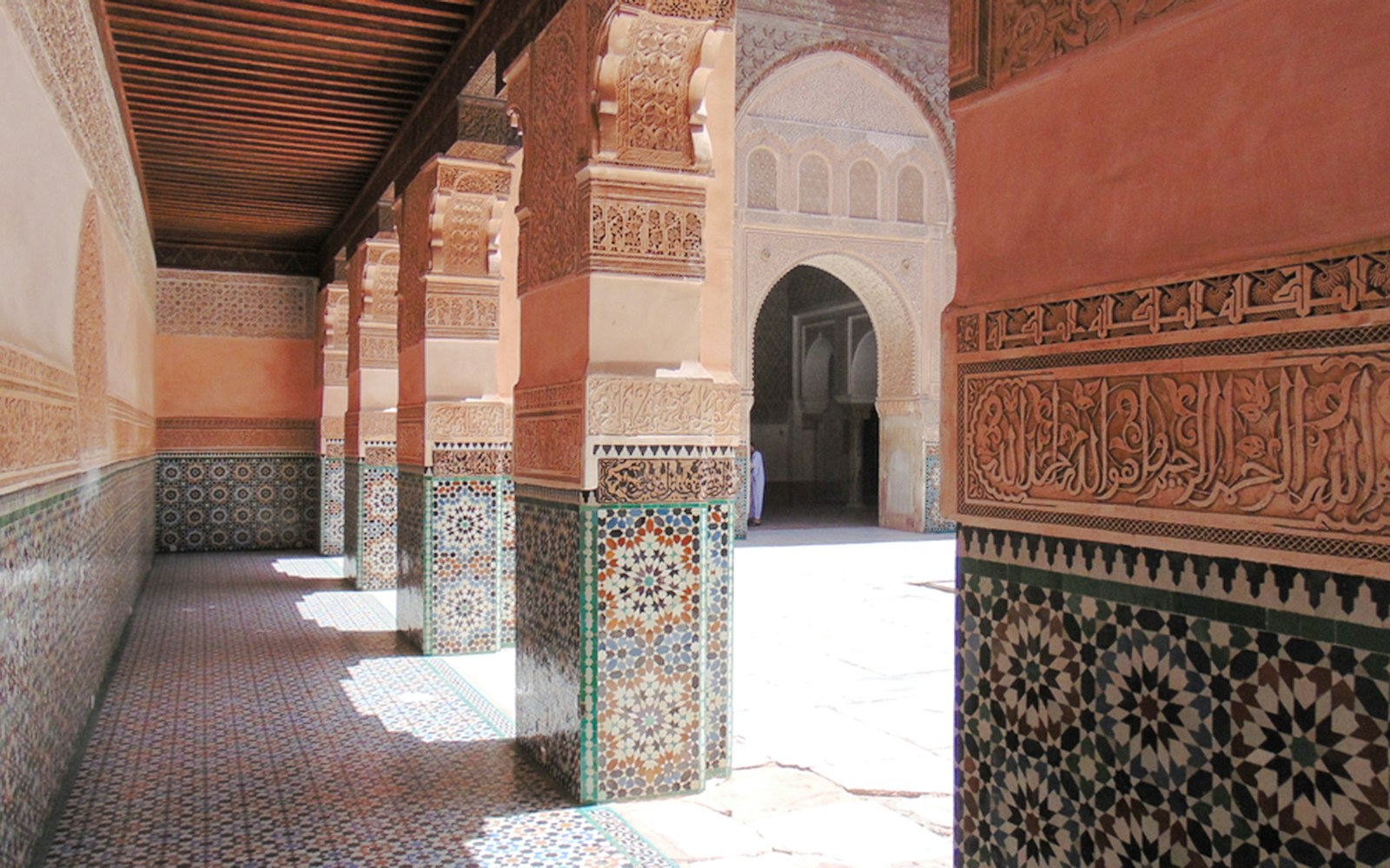 Ben Youssef Madrasa courtyard with intricate tilework and carved arches in Marrakech, Morocco.