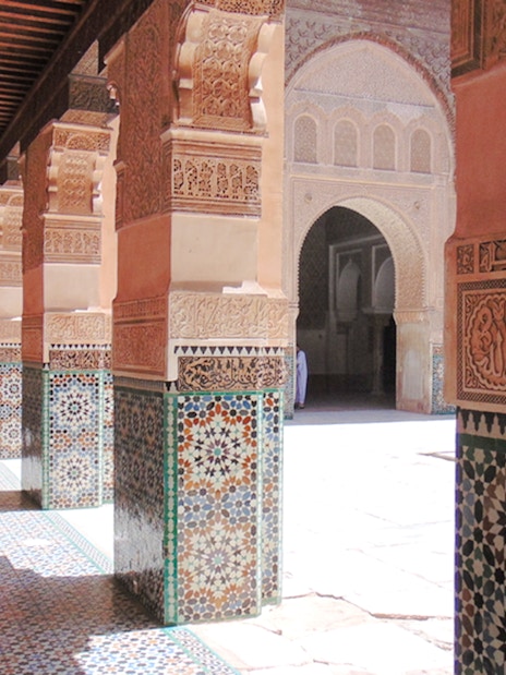 Ben Youssef Madrasa courtyard with intricate tilework and carved arches in Marrakech, Morocco.