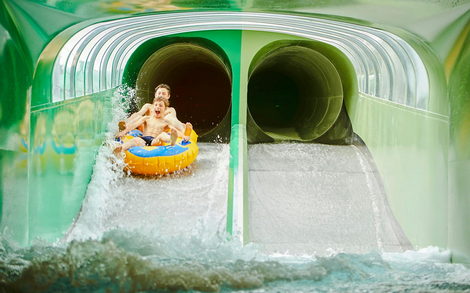 Two people on a raft sliding down a water slide at Splash Clash.