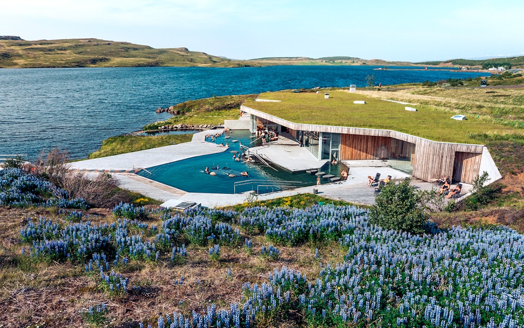 Vok Baths geothermal pools with people relaxing, surrounded by Icelandic landscape and lake.