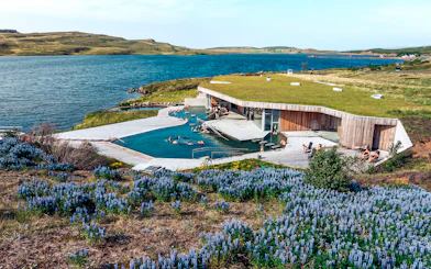 Vok Baths geothermal pools with people relaxing, surrounded by Icelandic landscape and lake.