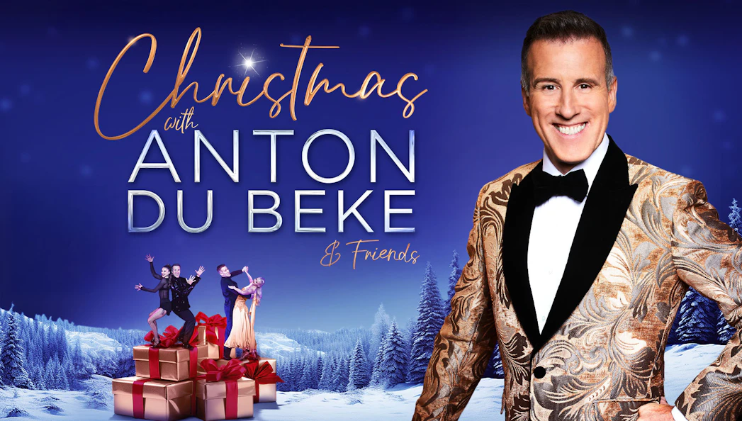 Christmas event with Anton Du Beke and dancers on gift boxes in snowy landscape.