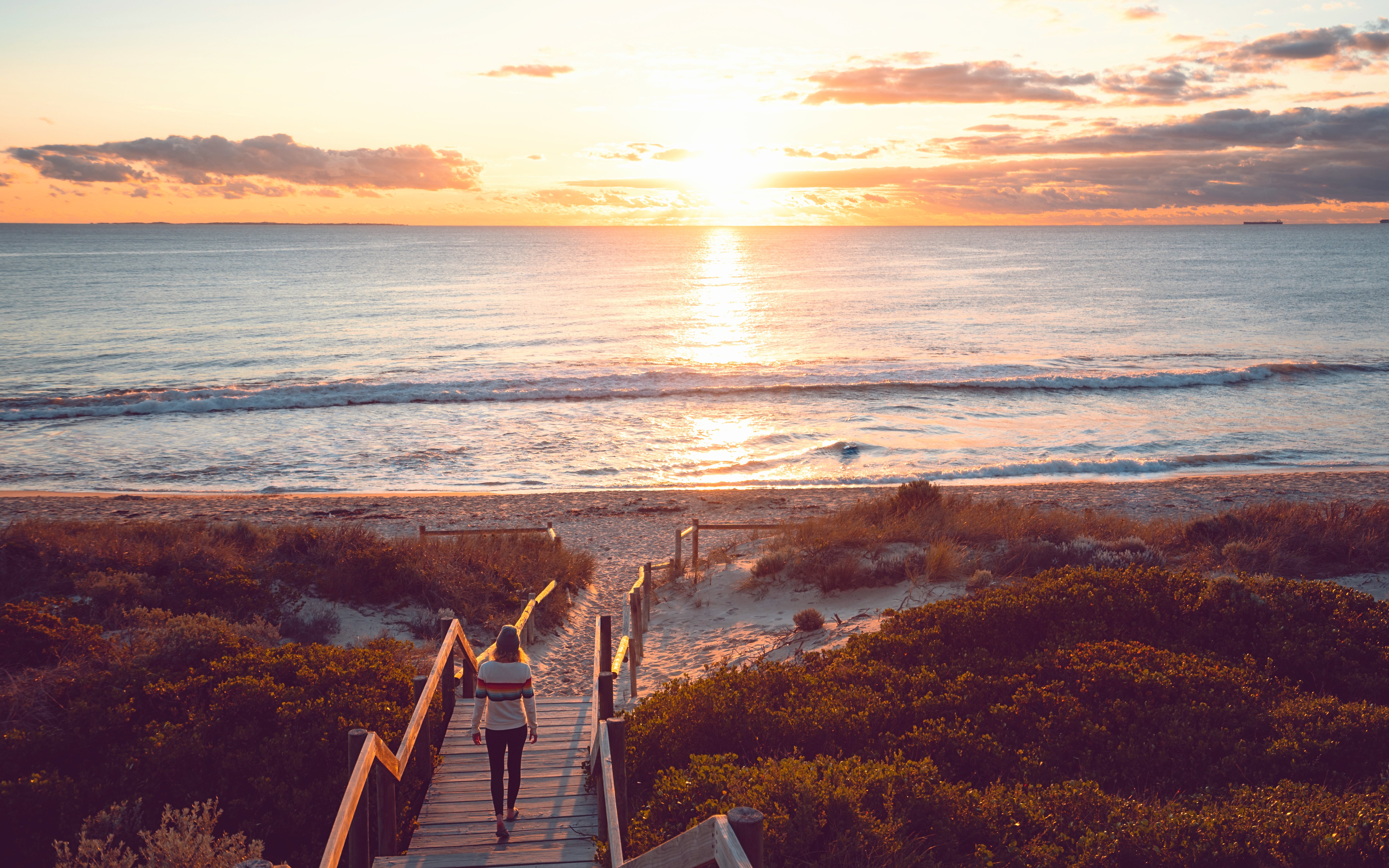 Young woman walking down the beach staircase at sunset, Perth