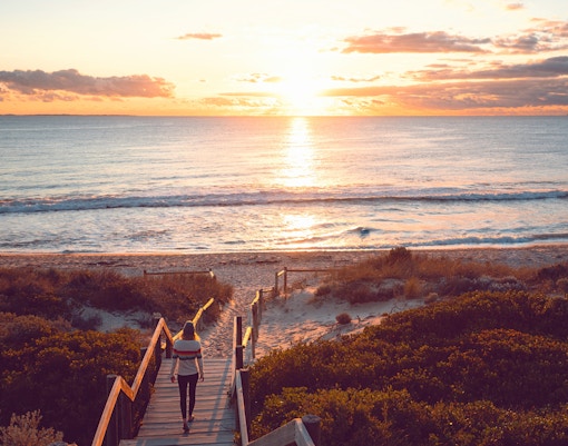 Young woman walking down the beach staircase at sunset, Perth