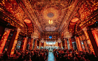 Vienna concert hall with audience and orchestra under ornate ceiling lighting.