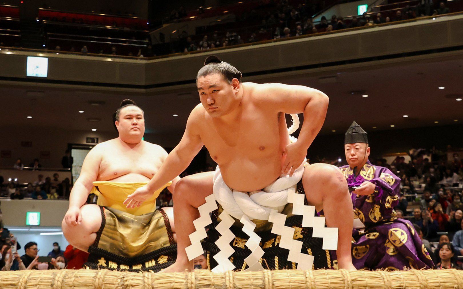 Sumo wrestlers preparing for a match in a Japanese arena.