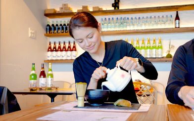 Young woman preparing matcha with Japanese sweets in a Tokyo tea room.