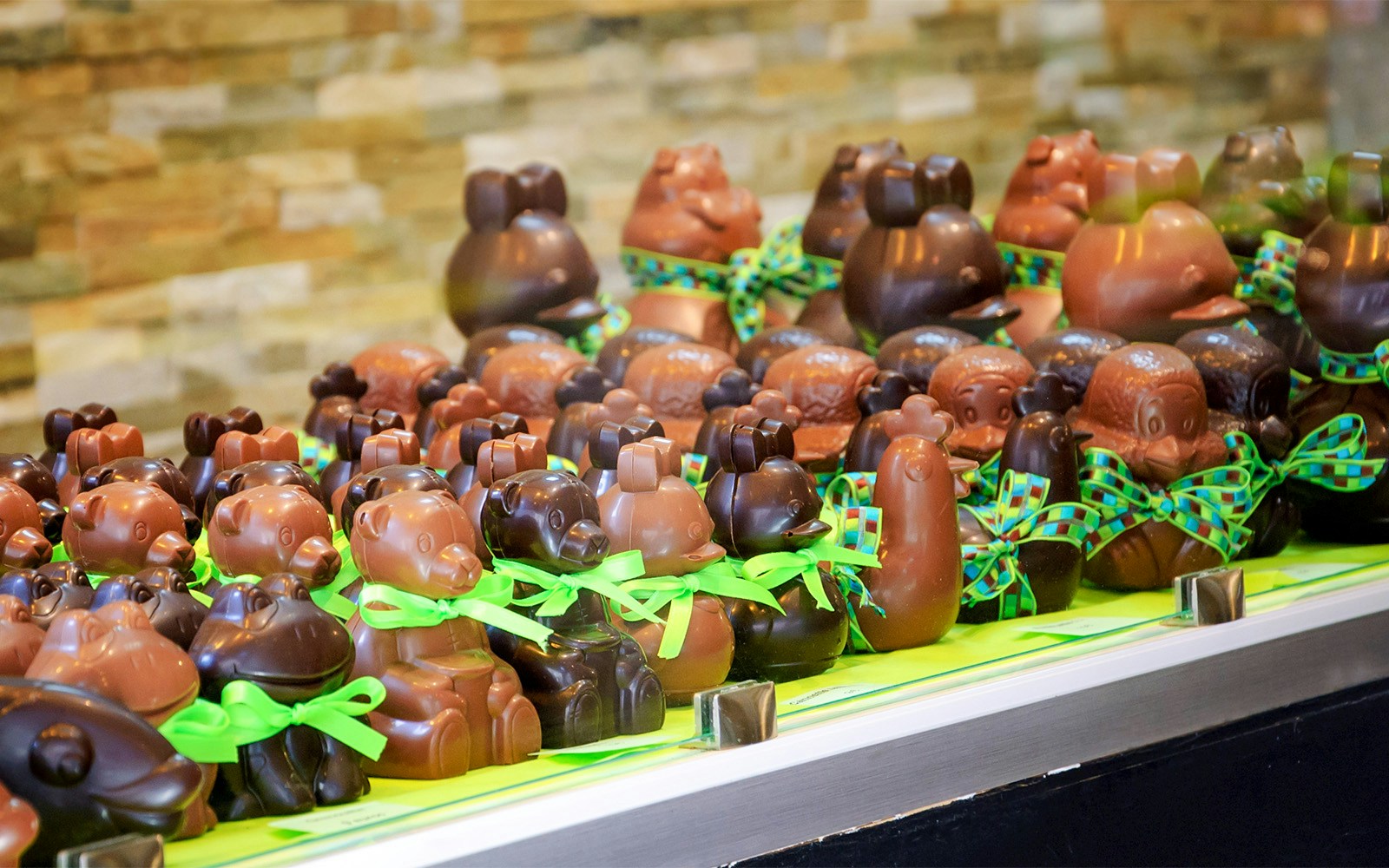 Parisian chocolatiers crafting intricate Easter eggs and bunnies in a workshop.