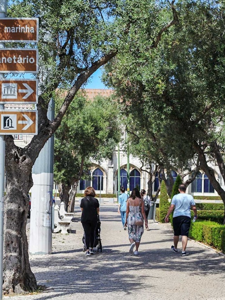 Signage for Navy Planetarium and Maritime Museum in Lisbon with people walking nearby.