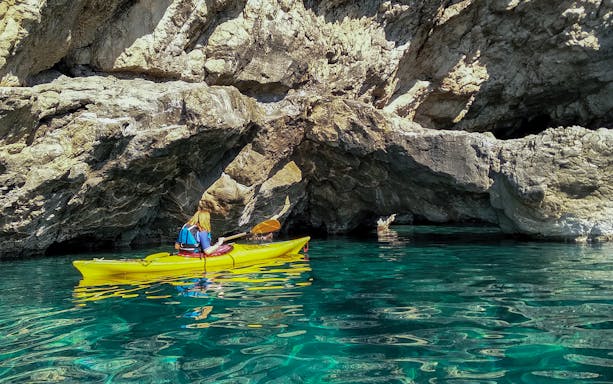 Kayaker exploring rocky coastline on Sorrento Coast tour to Crapolla Fjord.