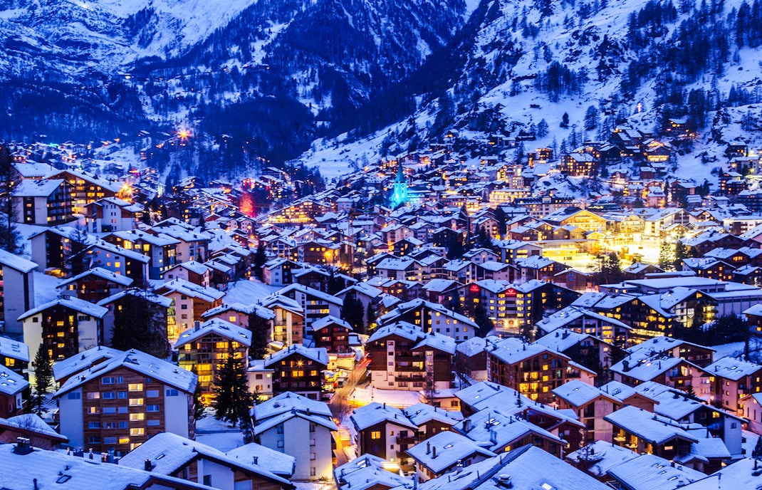 Zermatt town illuminated at twilight with snow-covered rooftops during Christmas.