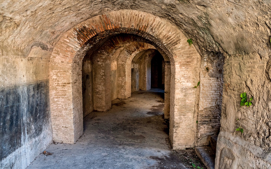 Ancient stone corridor in the Rome Catacombs with arched ceilings and walls.