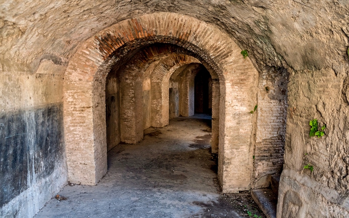 Ancient stone corridor in the Rome Catacombs with arched ceilings and walls.