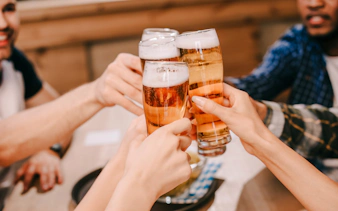 Multicultural friends clinking lager beer glasses in a pub.