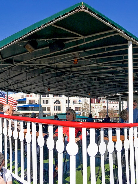 Steamboat Natchez deck with passengers, New Orleans skyline in background on Mississippi River.