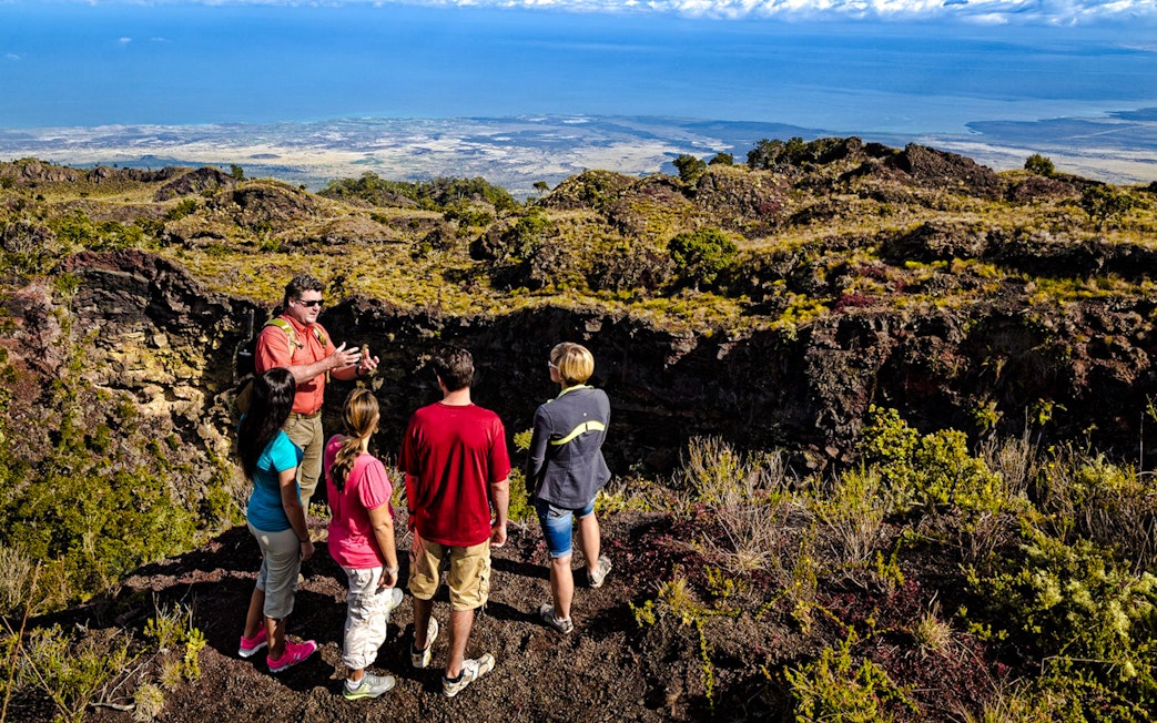 Guide showing visitors the edge of Hualalai volcano crater in Hawaii.