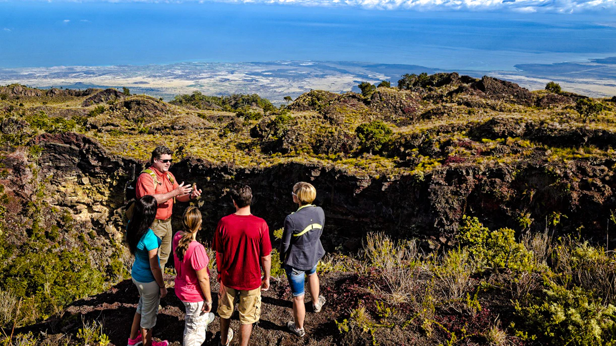 Guide showing visitors the edge of Hualalai volcano crater in Hawaii.