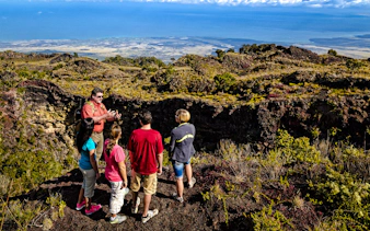 Guide showing visitors the edge of Hualalai volcano crater in Hawaii.
