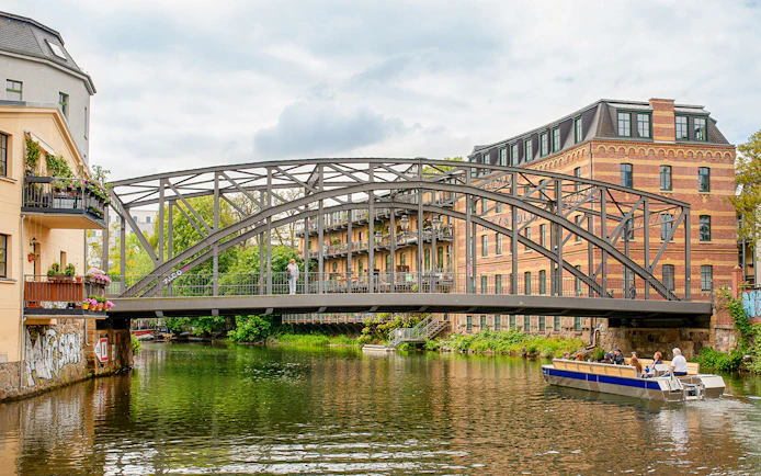 Motorboat tour on Karl Heine Canal in Leipzig passing under a historic bridge.