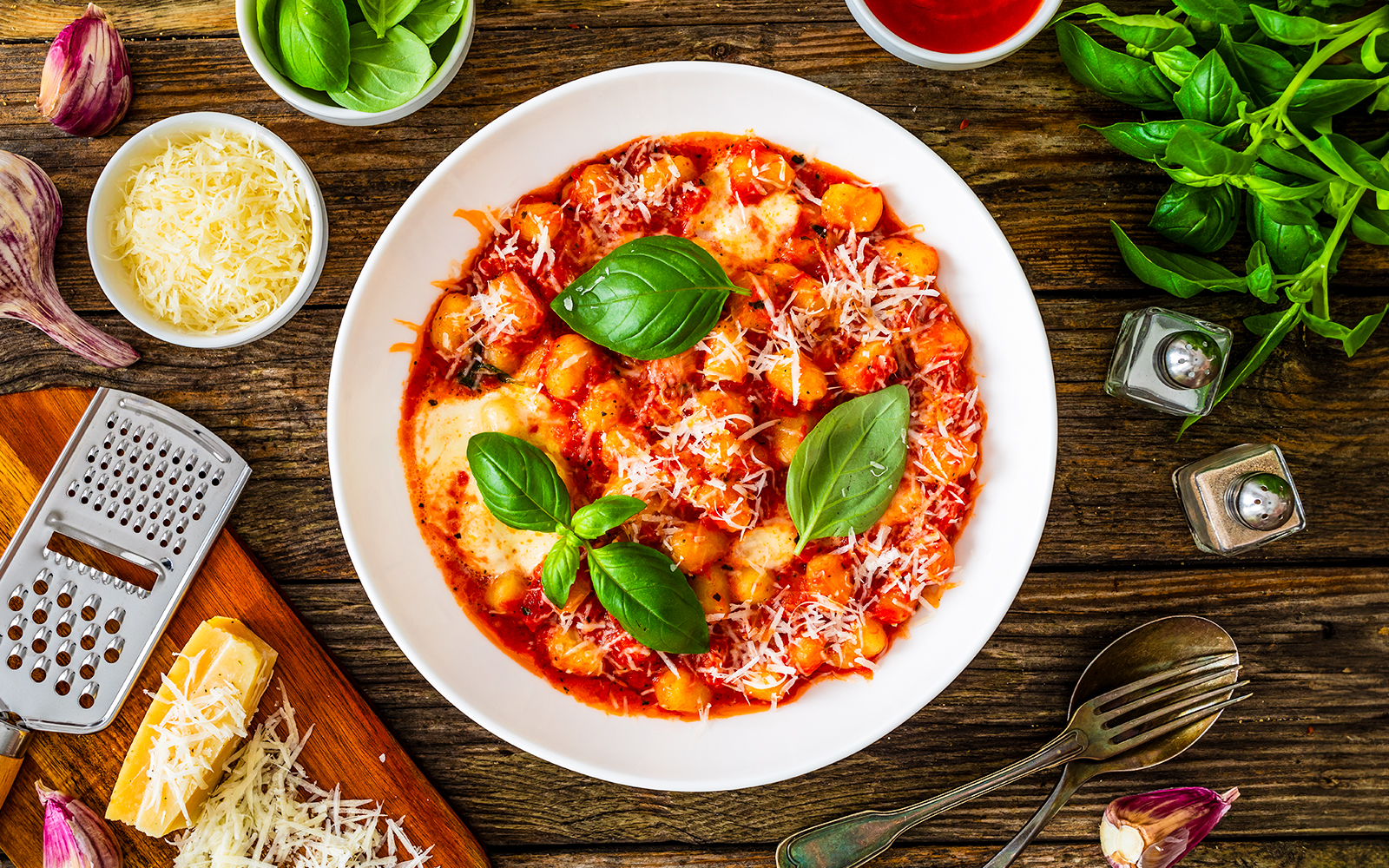 Gnocchi alla sorrentina with mozzarella, tomato sauce, and Parmigiano Reggiano on wooden table.