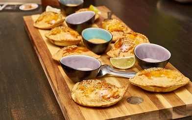 Pastries with sesame seeds and dipping sauces on a wooden board, St. Georg food tour.