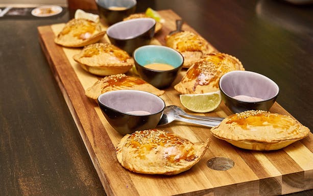 Pastries with sesame seeds and dipping sauces on a wooden board, St. Georg food tour.