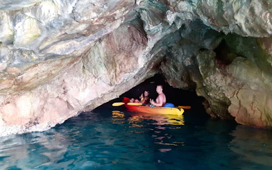 Kayakers exploring Betina Cave on a sunset tour near Old Town Walls and Lokrum Island.