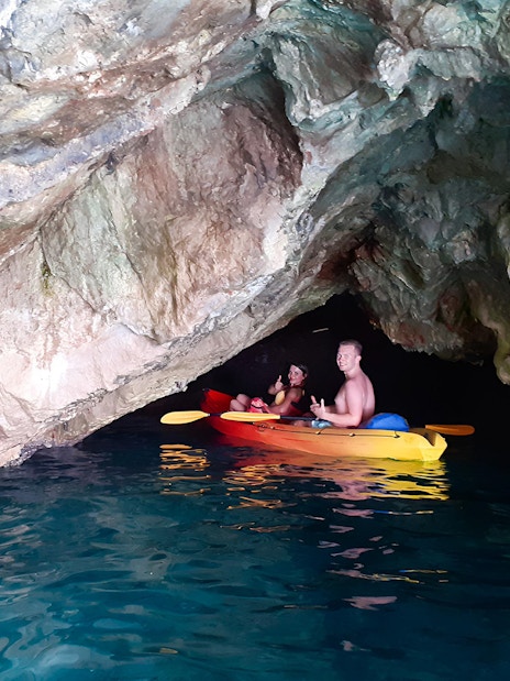 Kayakers exploring Betina Cave on a sunset tour near Old Town Walls and Lokrum Island.