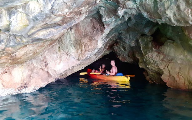 Kayakers exploring Betina Cave on a sunset tour near Old Town Walls and Lokrum Island.