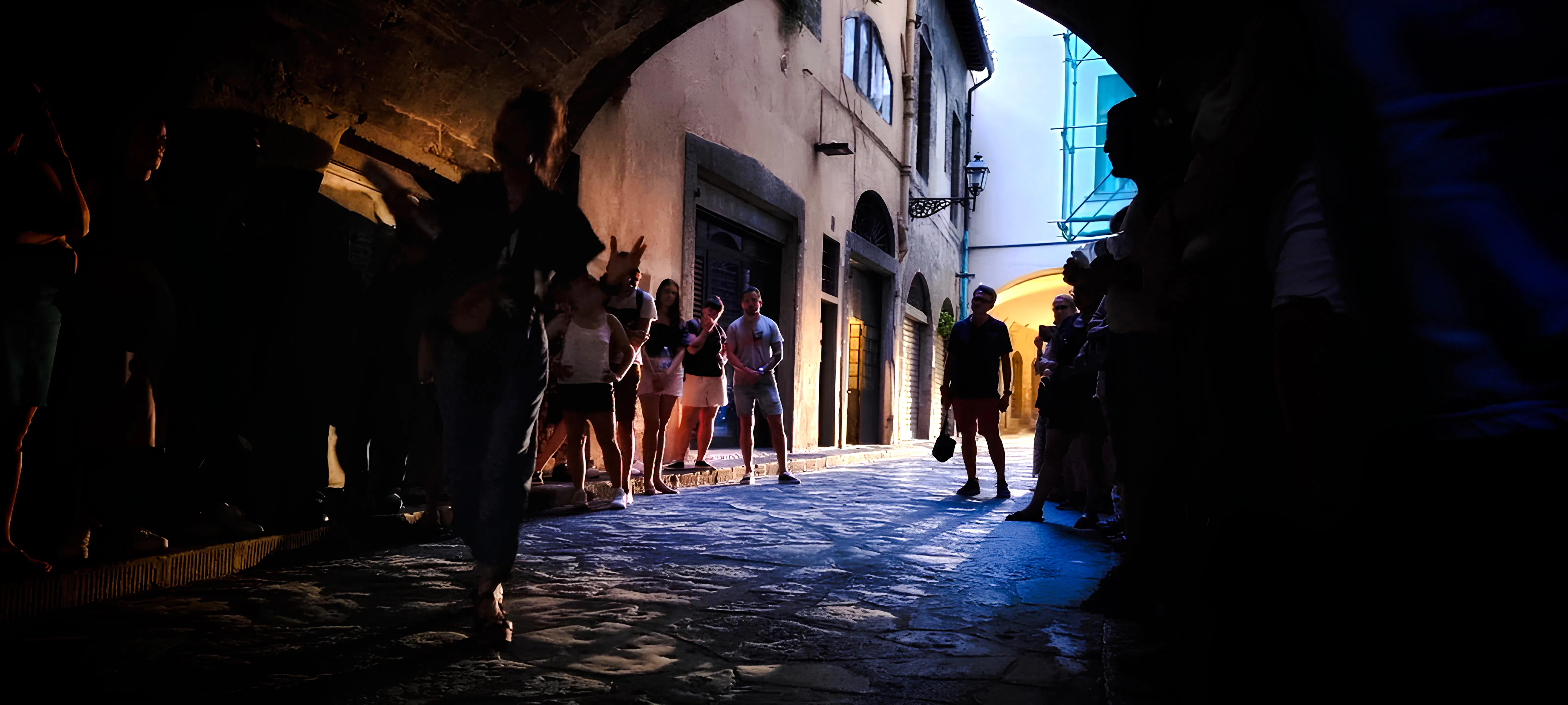 Tour group exploring a dimly lit alley in Florence, highlighting the city's mysteries and legends.