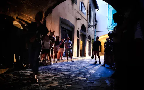 Tour group exploring a dimly lit alley in Florence, highlighting the city's mysteries and legends.