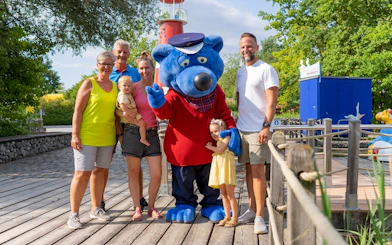 Family with mascot at Ravensburger Spieleland.