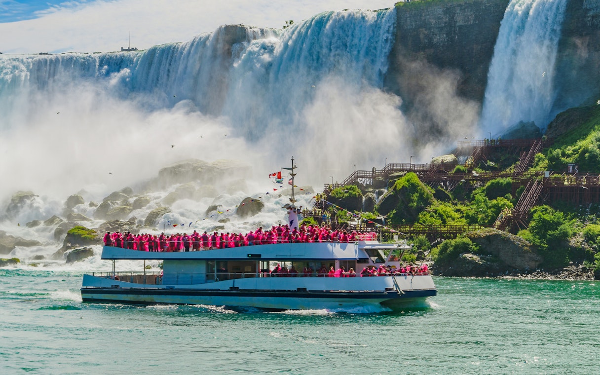 Boat cruise approaching Niagara Falls with passengers in pink raincoats.