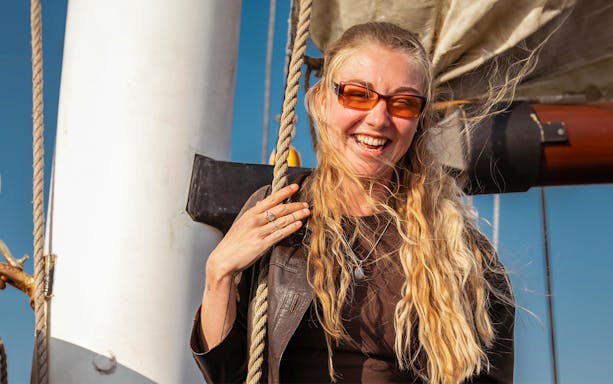 Person enjoying a boat tour in Amsterdam, holding a rope on deck.