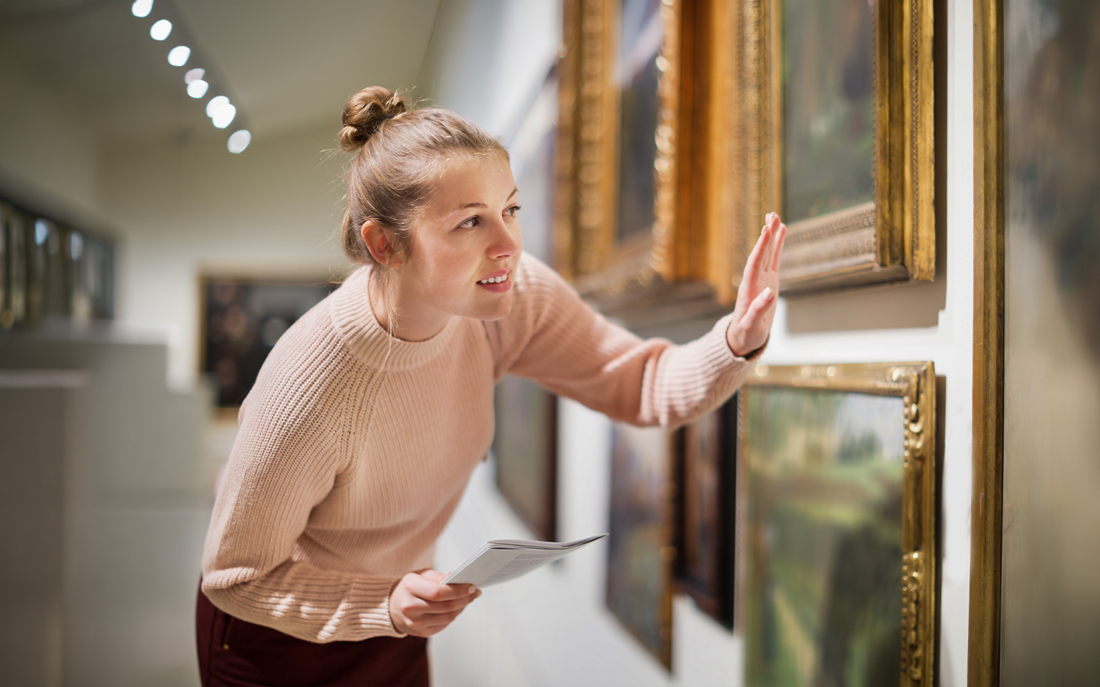 Woman examining paintings with guide in art museum.
