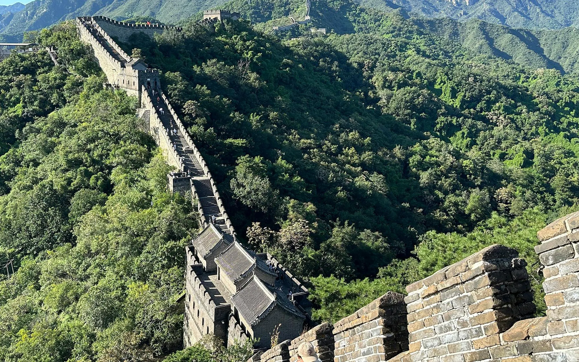Mutianyu Great Wall section with lush greenery, showcasing ancient stone architecture.