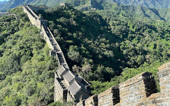 Mutianyu Great Wall section with lush greenery, showcasing ancient stone architecture.