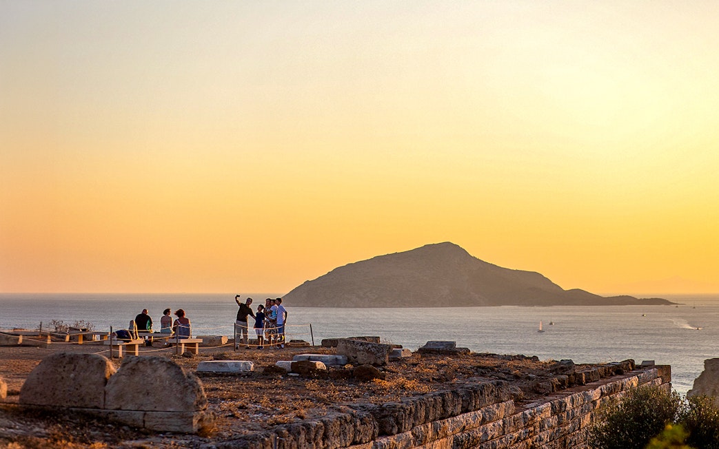 Tourists taking selfie at sunset in Archaeological Site of Sounion, Greece.
