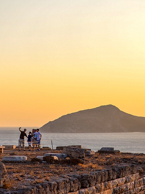 Tourists taking selfie at sunset in Archaeological Site of Sounion, Greece.