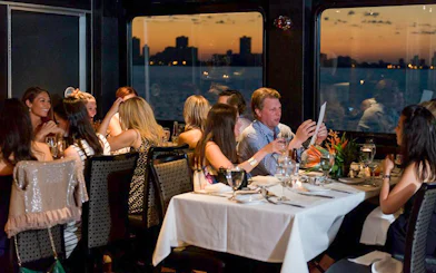 Guests dining on Odyssey Lake Michigan Dinner Cruise at sunset.