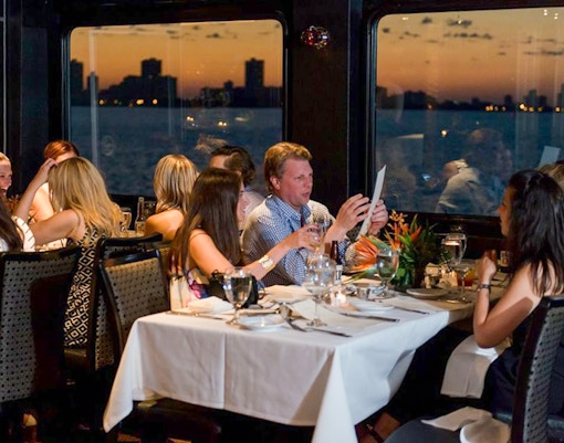 Guests dining on Odyssey Lake Michigan Dinner Cruise at sunset.