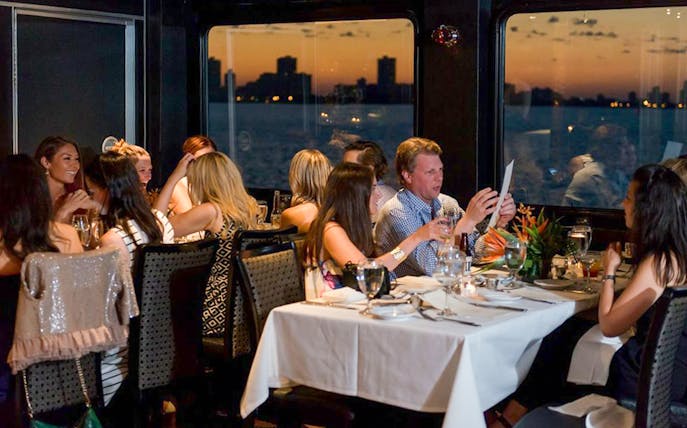 Guests dining on Odyssey Lake Michigan Dinner Cruise at sunset.