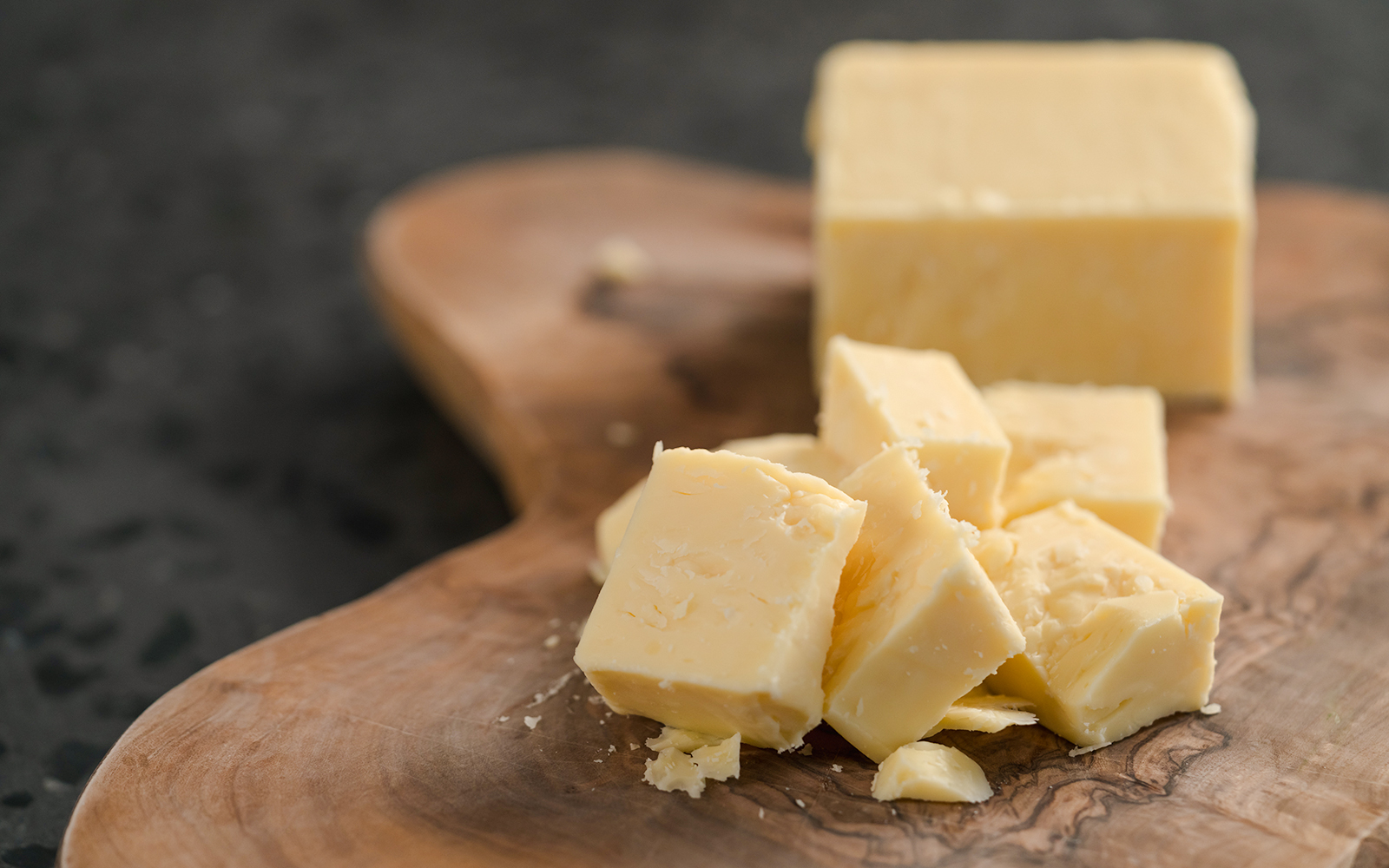 White cheddar cheese pieces on a wooden board at Cheese Museum in Paris.