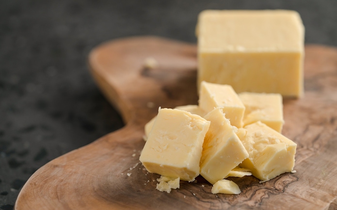White cheddar cheese pieces on a wooden board at Cheese Museum in Paris.