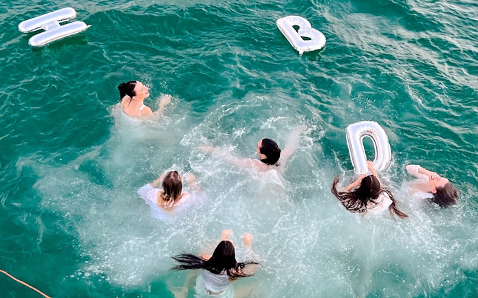 Tourists swimming with inflatable letters in the sea during a luxury yacht tour in Dubai.