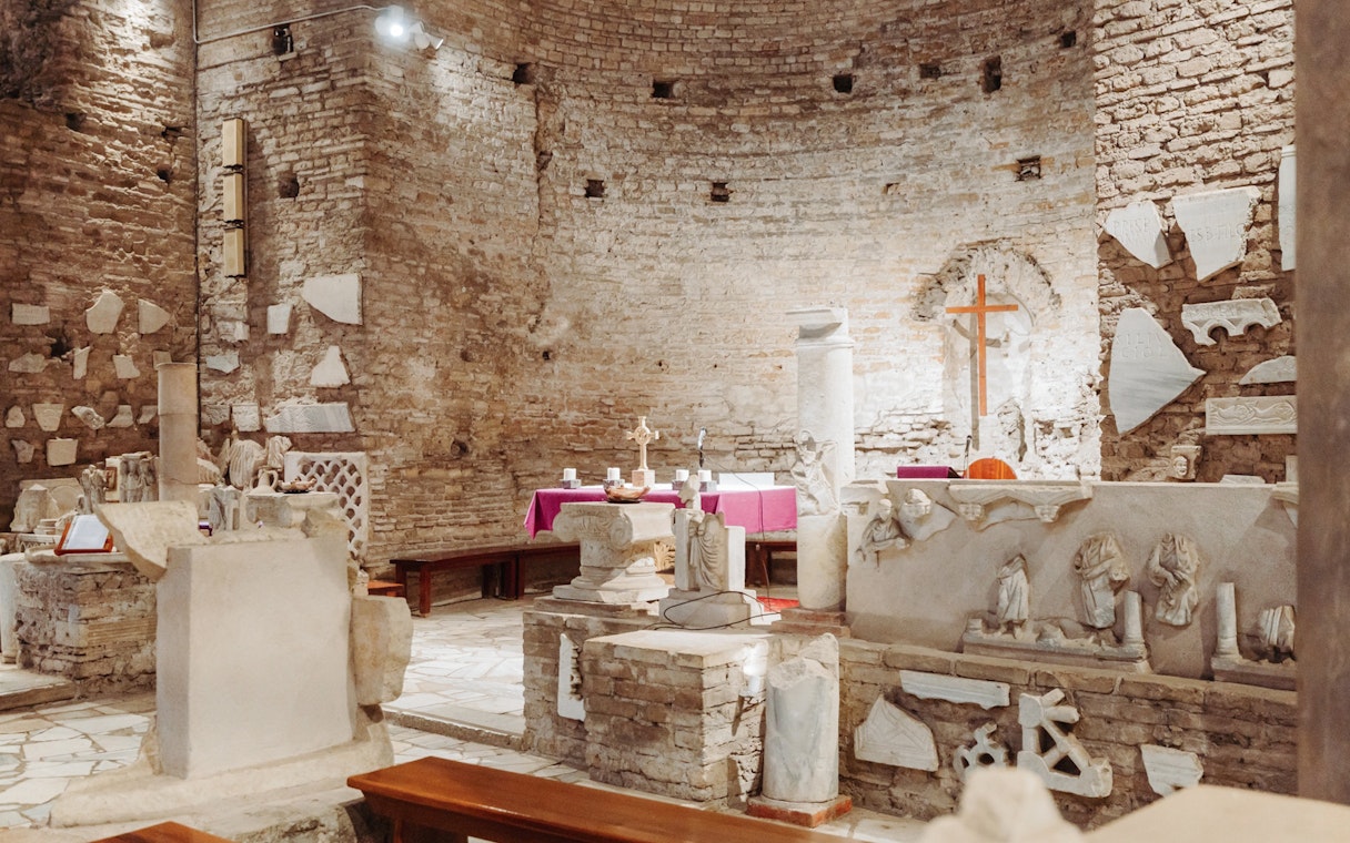 Underground Rome catacombs with ancient stone relics and altar on the Appian Way.