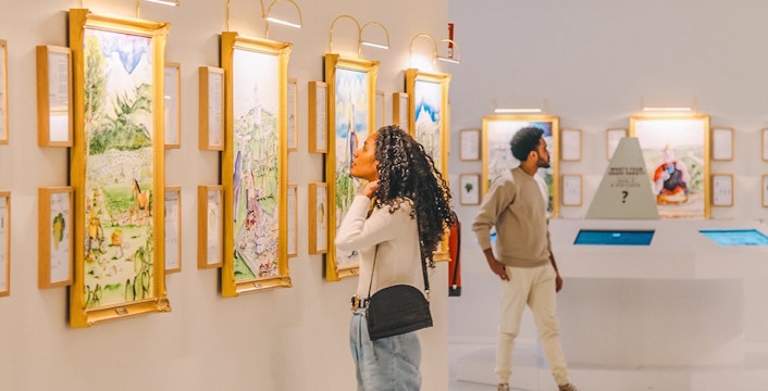 Visitors viewing wine-themed art in a gallery during The Wine Experience tour.