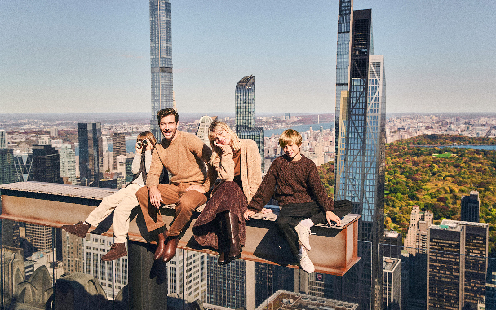 Family sitting on a beam with New York skyline view from Top of the Rock.