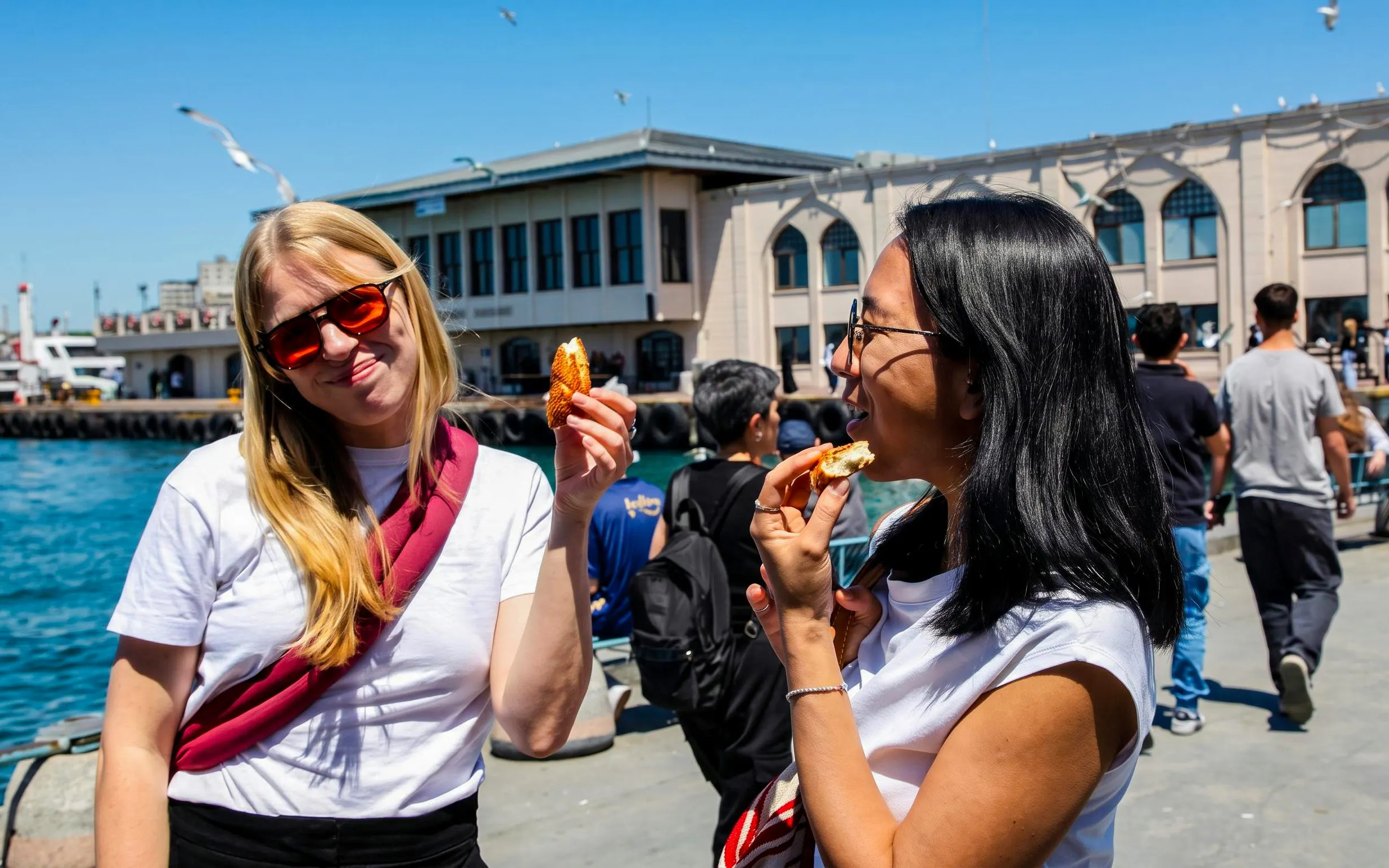 Tourists enjoying simit by the waterfront in Istanbul during a food tour.