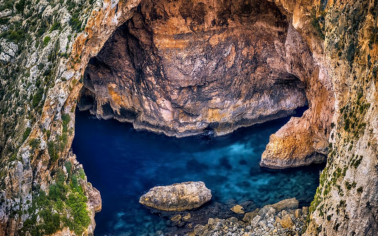 Blue Grotto sea cave with clear blue water and rocky cliffs in Malta.